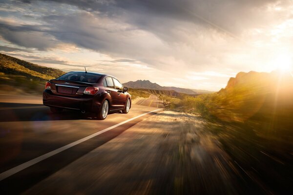 Subaru ao pôr do sol corre pela estrada