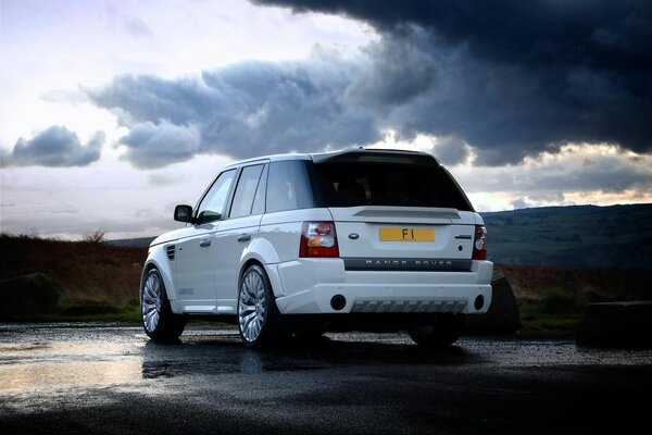 Range rover em asfalto molhado em meio a uma nuvem