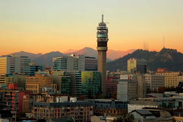 Uma cidade com uma torre no centro e montanhas no fundo
