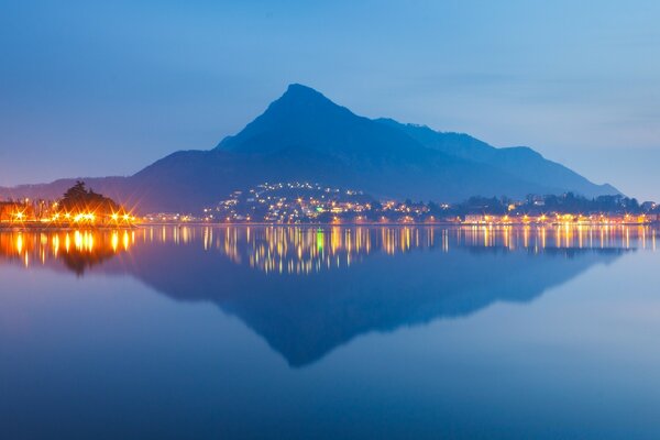 Reflexão das montanhas e das luzes da cidade na água
