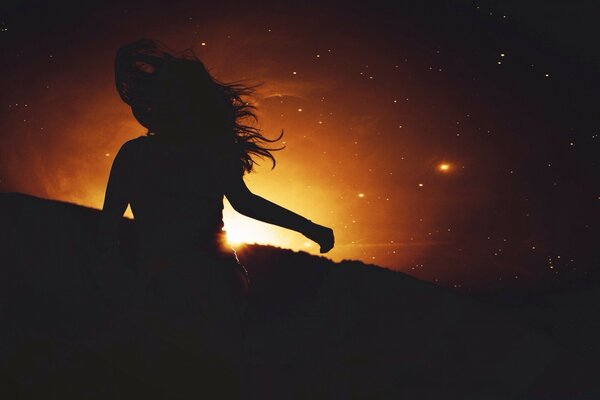 Silhueta escura da menina ao pôr do sol