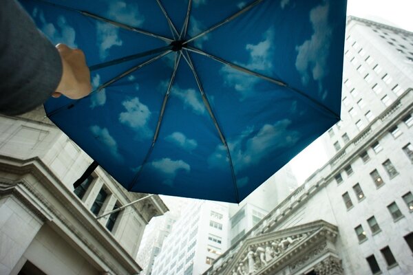 Guarda-chuva azul com nuvens perto de casas grandes