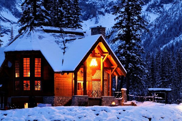 Casa nas montanhas cobertas de neve da floresta de Inverno