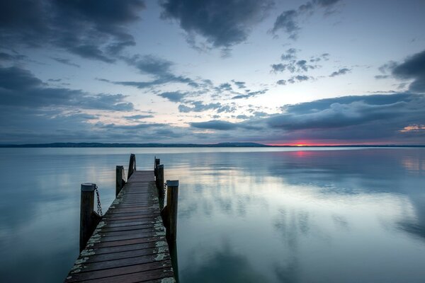 No lago ao pôr do sol vai estreita ponte