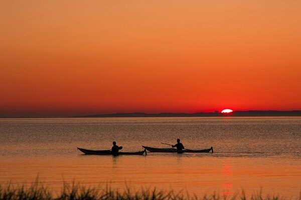 Pessoas nadam em barcos durante o pôr do sol